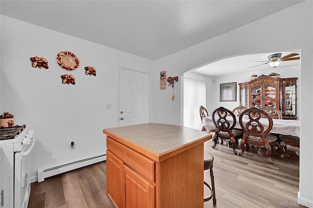 kitchen featuring baseboard heating, gas range gas stove, a kitchen island, and light hardwood / wood-style flooring