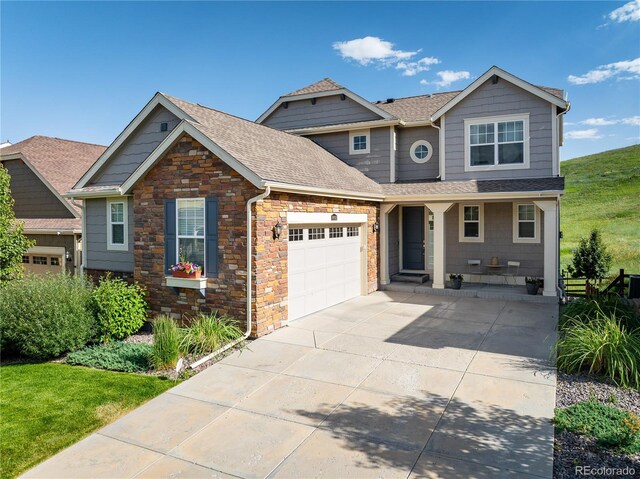 18992 W 84th Ave, Arvada, CO 80007 - craftsman-style house featuring a porch, a garage, concrete driveway, stone siding, and a shingled roof
