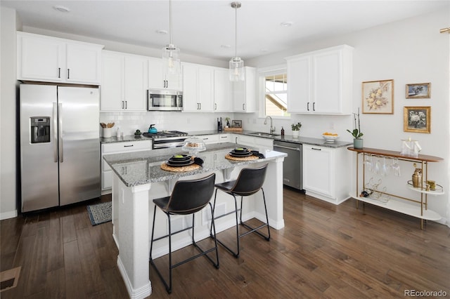 18992 W 84th Ave, Arvada, CO 80007 - kitchen featuring stainless steel appliances, dark wood-style floors, a kitchen island, light stone countertops, and white cabinetry