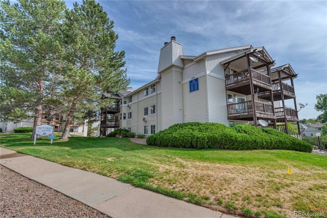 17595 E Mansfield Ave Unit 1331L, Aurora, CO 80013 - view of property exterior with a chimney, a lawn, and a balcony