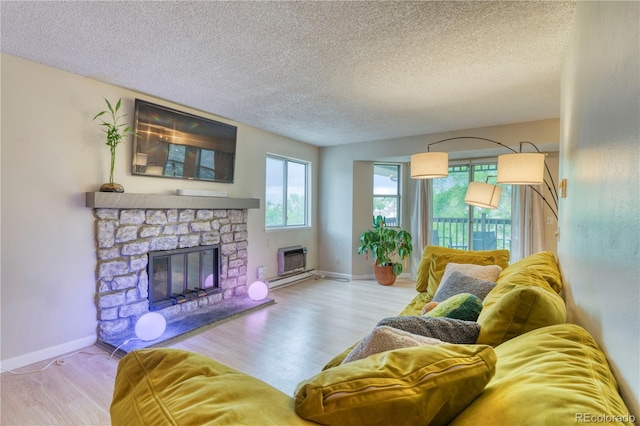 17595 E Mansfield Ave Unit 1331L, Aurora, CO 80013 - living room with a stone fireplace, wood finished floors, baseboards, a textured ceiling, and an AC wall unit