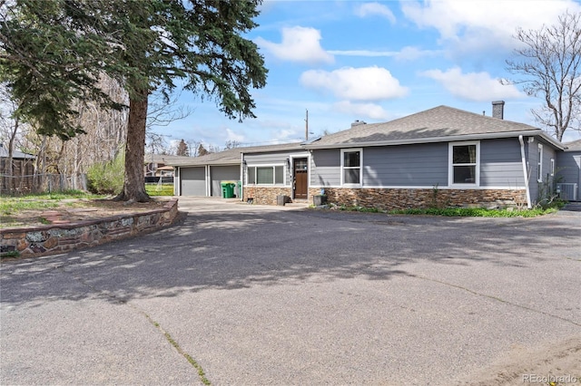 3625 Chase St, Wheat Ridge, CO 80212 - single story home with an attached garage, stone siding, asphalt driveway, a chimney, and central AC unit
