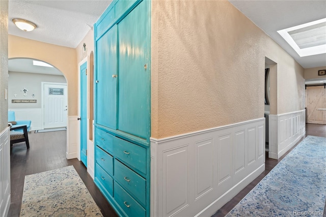 3625 Chase St, Wheat Ridge, CO 80212 - hallway featuring wainscoting, arched walkways, a decorative wall, dark wood-style floors, and a skylight
