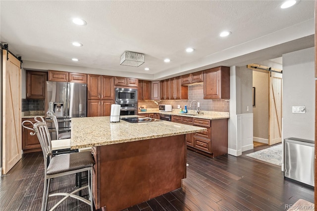 3625 Chase St, Wheat Ridge, CO 80212 - kitchen featuring a barn door, stainless steel appliances, a sink, decorative backsplash, and recessed lighting