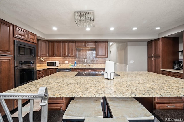 3625 Chase St, Wheat Ridge, CO 80212 - kitchen with black appliances, a sink, a large island, tasteful backsplash, and light stone countertops