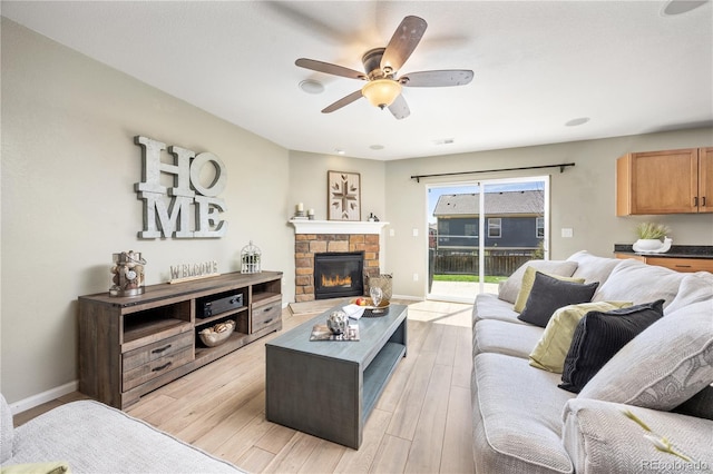 living area featuring ceiling fan, a stone fireplace, light wood-style flooring, recessed lighting, and baseboards