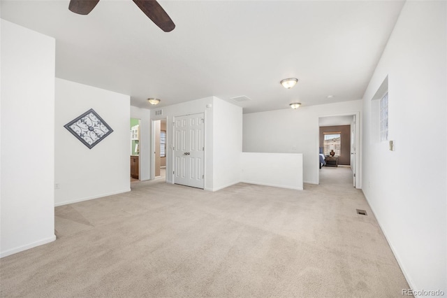 unfurnished living room featuring ceiling fan, visible vents, light carpet, and baseboards