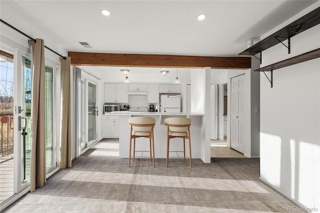 kitchen with light colored carpet, light countertops, beam ceiling, freestanding refrigerator, and stainless steel microwave