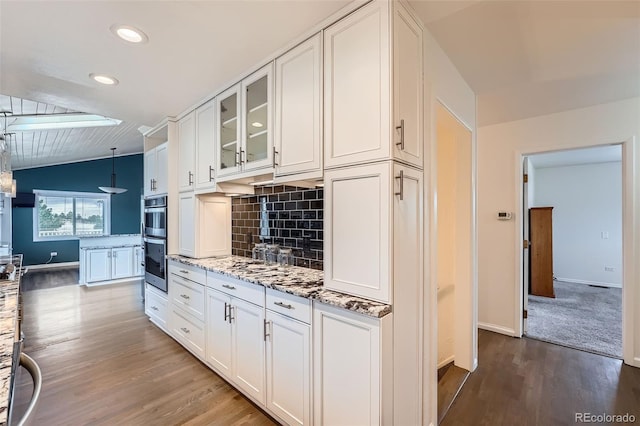 12189 Boot Hill Dr, Parker, CO 80138 - kitchen featuring wood finished floors, double oven, backsplash, white cabinets, and baseboards
