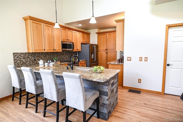588 Stafford Cir, Castle Rock, CO 80104 - kitchen featuring stainless steel appliances, a peninsula, tasteful backsplash, light wood-style flooring, and a breakfast bar