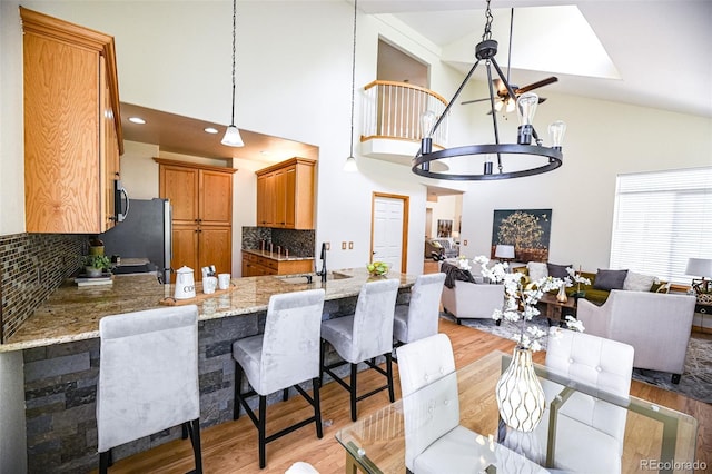 588 Stafford Cir, Castle Rock, CO 80104 - kitchen featuring open floor plan, light wood-style flooring, light stone countertops, a peninsula, and high vaulted ceiling