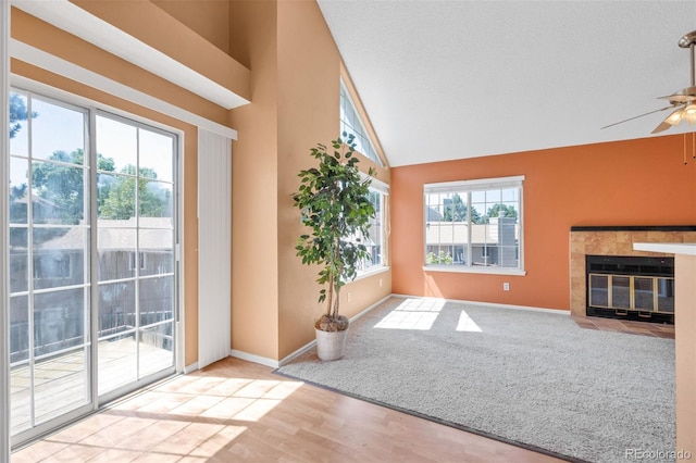 13782 E Lehigh Ave Unit H, Aurora, CO 80014 - unfurnished living room with a ceiling fan, wood finished floors, a tiled fireplace, and high vaulted ceiling