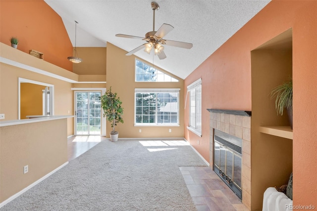 13782 E Lehigh Ave Unit H, Aurora, CO 80014 - unfurnished living room featuring a tiled fireplace, high vaulted ceiling, ceiling fan, carpet, and a textured ceiling
