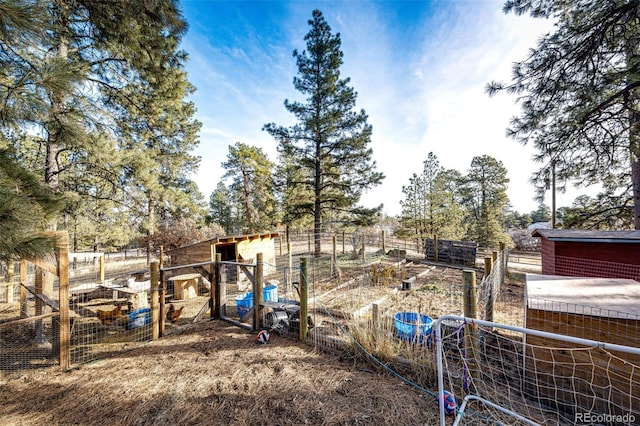 view of yard with fence, a vegetable garden, and an outbuilding