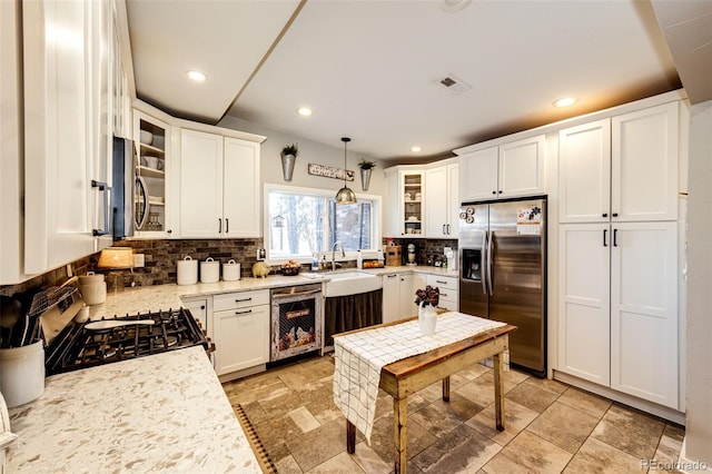 kitchen with hanging light fixtures, backsplash, beverage cooler, and stainless steel appliances