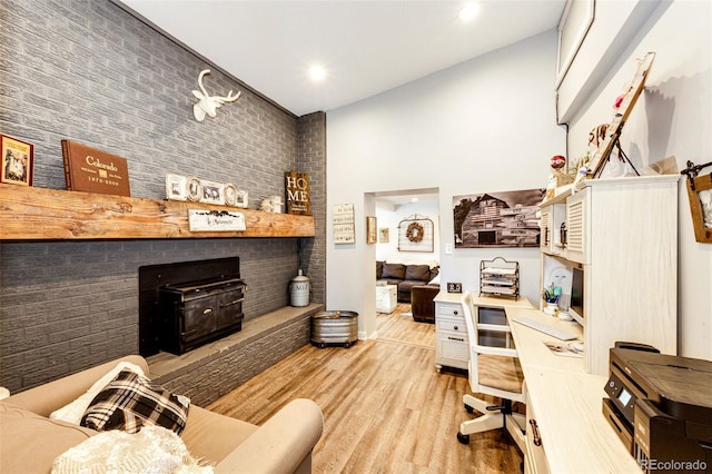 living room with brick wall, a towering ceiling, and light hardwood / wood-style flooring