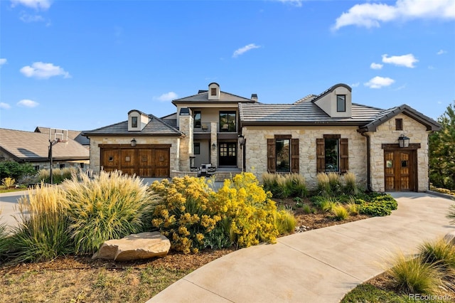 view of front of home featuring an attached garage, stone siding, and concrete driveway