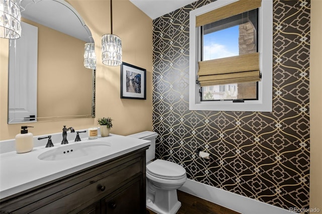 bathroom featuring vanity, toilet, wallpapered walls, and wood finished floors