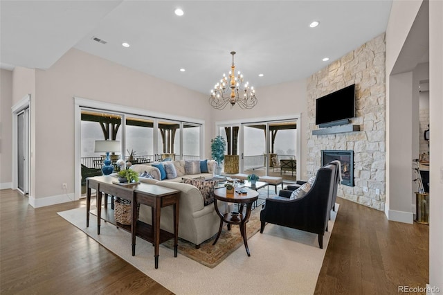 living area featuring a chandelier, a stone fireplace, recessed lighting, wood finished floors, and visible vents