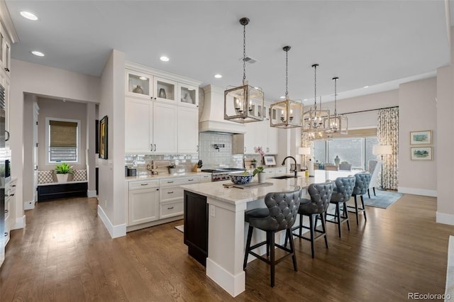 kitchen with backsplash, range, baseboards, a notable chandelier, and custom range hood