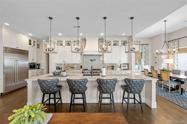 kitchen with dark wood-style floors, a chandelier, stainless steel built in fridge, and premium range hood