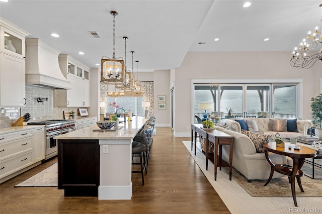 kitchen featuring an inviting chandelier, premium range hood, high end range, backsplash, and visible vents