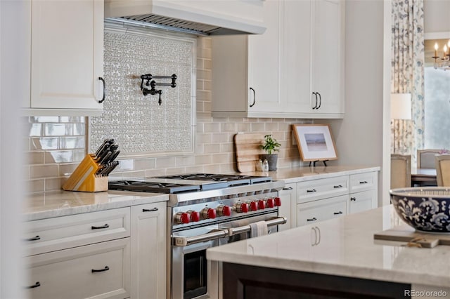 kitchen featuring backsplash, double oven range, light stone counters, custom range hood, and white cabinetry