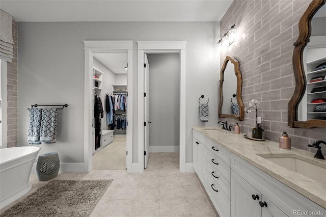 full bathroom with tile patterned flooring, a sink, a spacious closet, and double vanity