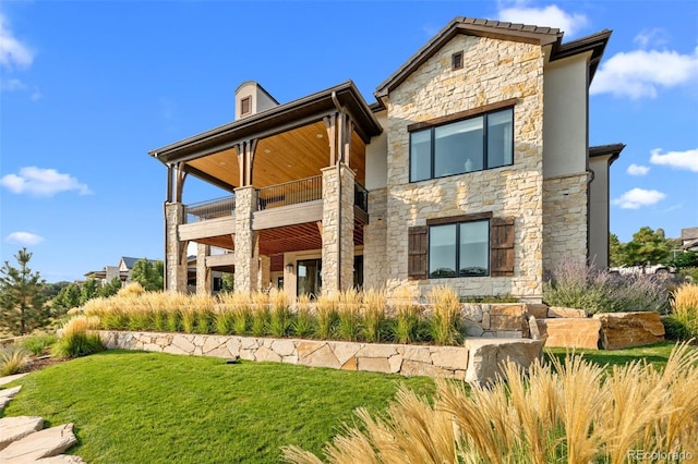 rear view of property featuring a yard and stone siding