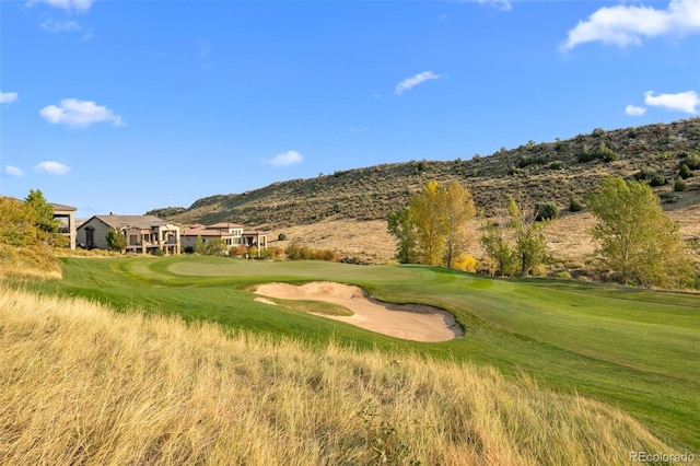 view of community featuring a lawn, a mountain view, and golf course view