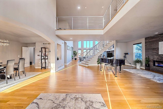 foyer with hardwood / wood-style floors, a towering ceiling, and a fireplace