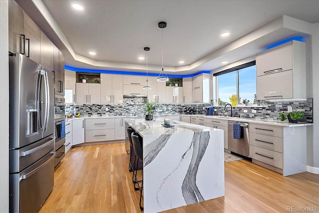 kitchen featuring decorative light fixtures, white cabinetry, light hardwood / wood-style flooring, appliances with stainless steel finishes, and a large island