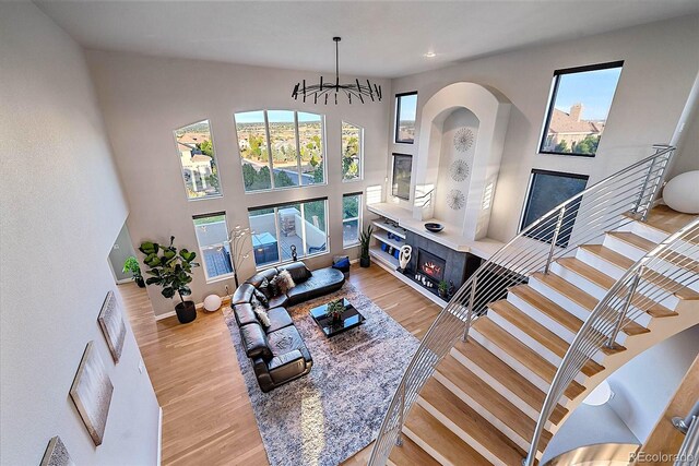 living room featuring light wood-type flooring, a towering ceiling, and a notable chandelier