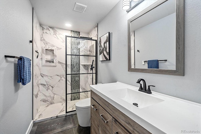 bathroom with toilet, vanity, and tiled shower