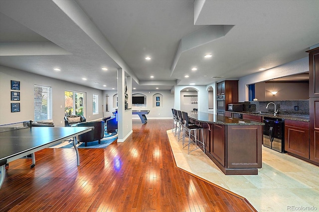 kitchen with a kitchen island, dark stone counters, a kitchen breakfast bar, sink, and oven