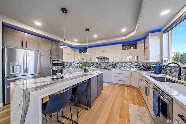 kitchen with decorative light fixtures, a kitchen island, sink, appliances with stainless steel finishes, and a breakfast bar area