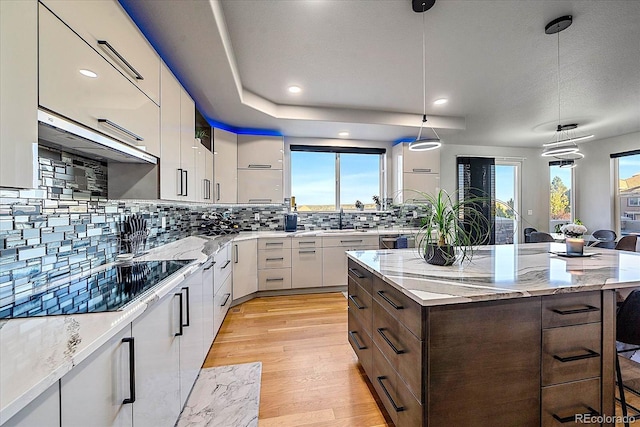 kitchen featuring a kitchen island, a kitchen bar, white cabinets, and hanging light fixtures