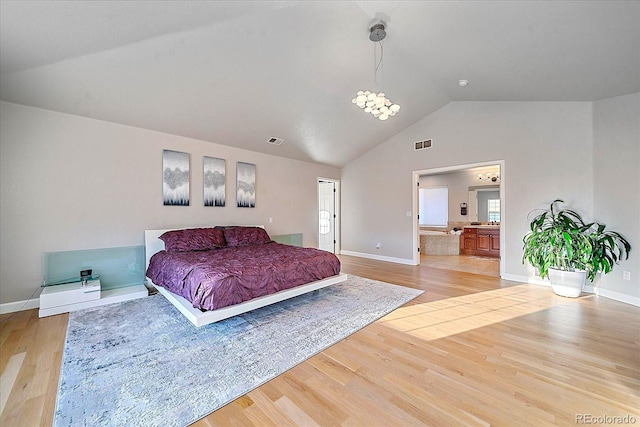 bedroom featuring ensuite bathroom, light hardwood / wood-style flooring, and vaulted ceiling