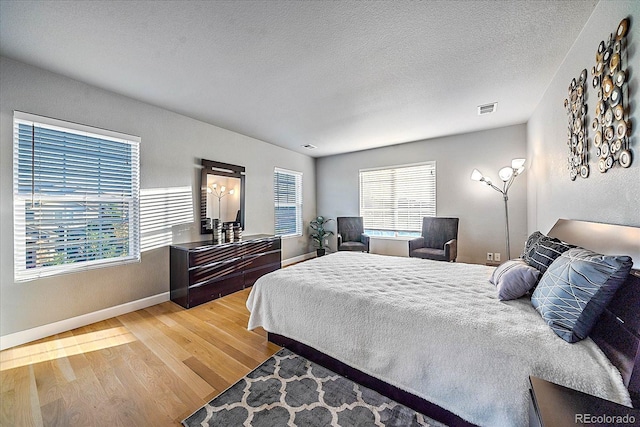 bedroom with a textured ceiling, hardwood / wood-style floors, and multiple windows