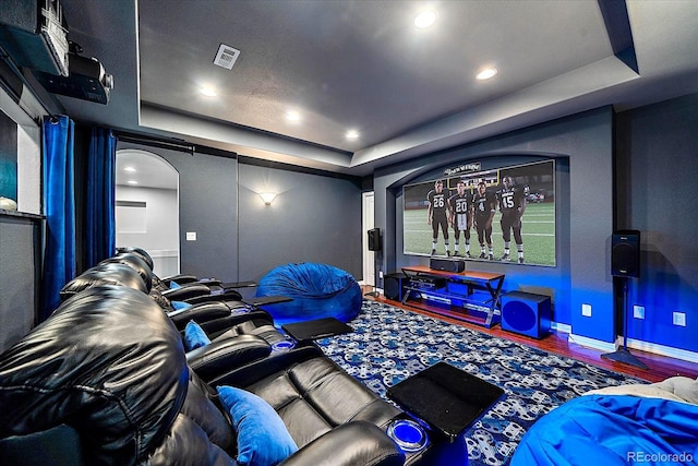 cinema room with a tray ceiling and hardwood / wood-style floors