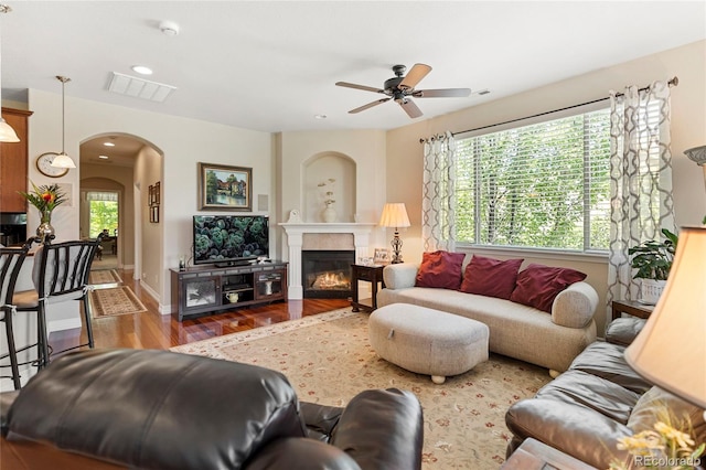10064 Bluffmont Ct, Lone Tree, CO 80124 - living room with wood finished floors, ceiling fan, arched walkways, a glass covered fireplace, and recessed lighting