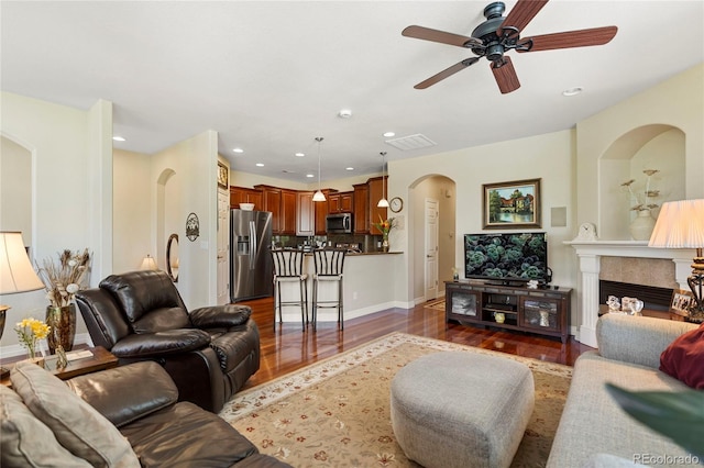 10064 Bluffmont Ct, Lone Tree, CO 80124 - living area with arched walkways, dark wood-style floors, a ceiling fan, a fireplace, and recessed lighting