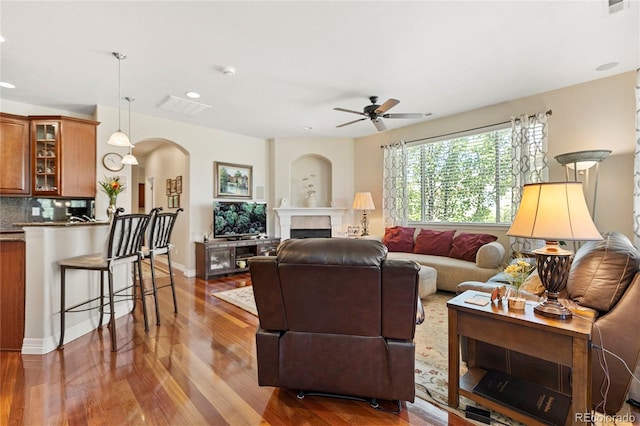 10064 Bluffmont Ct, Lone Tree, CO 80124 - living room featuring arched walkways, a ceiling fan, wood finished floors, recessed lighting, and a fireplace