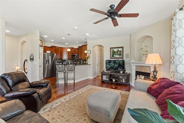10064 Bluffmont Ct, Lone Tree, CO 80124 - living room with arched walkways, dark wood-style floors, a ceiling fan, recessed lighting, and a glass covered fireplace