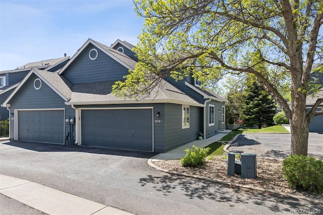 4976 S Nelson St Unit A, Littleton, CO 80127 - view of front of house featuring an attached garage, roof with shingles, and driveway