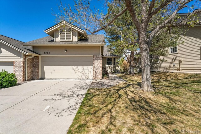 view of front of house with brick siding, an attached garage, driveway, and a front lawn