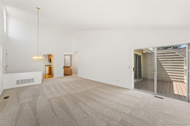 unfurnished room with carpet, a chandelier, and high vaulted ceiling