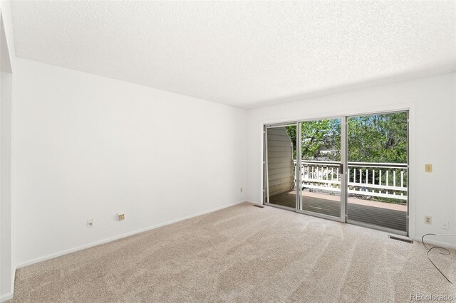 carpeted spare room with a textured ceiling and baseboards
