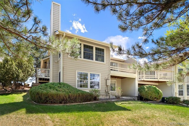 view of front of house with a chimney, a front lawn, and a balcony