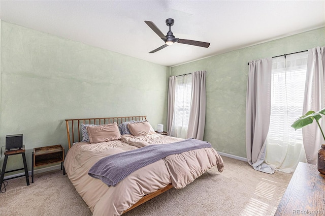 bedroom with multiple windows, light carpet, and ceiling fan